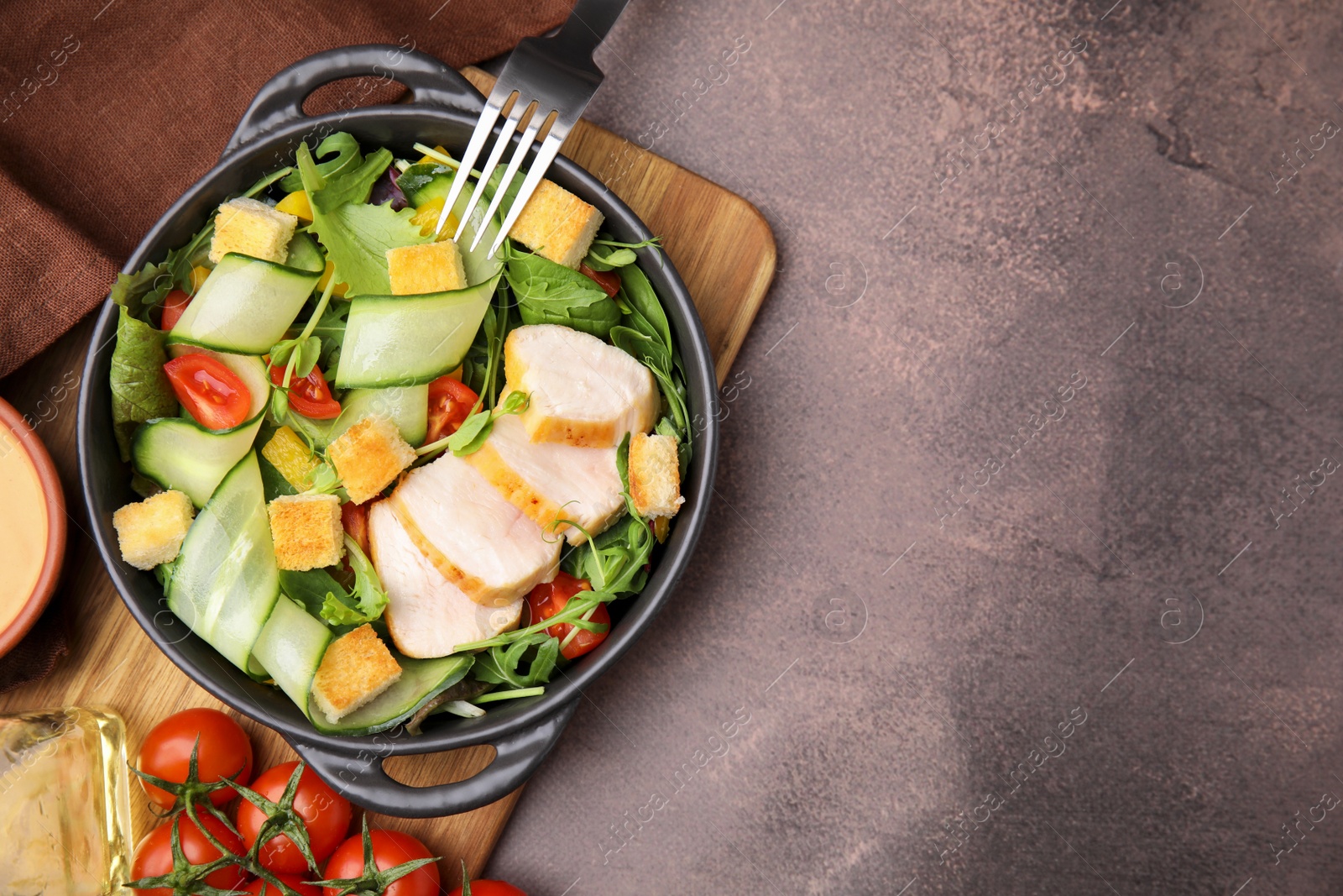 Photo of Delicious salad with croutons, chicken and vegetables served on grey table, flat lay. Space for text