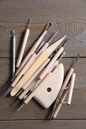 Set of different clay crafting tools on wooden table, top view