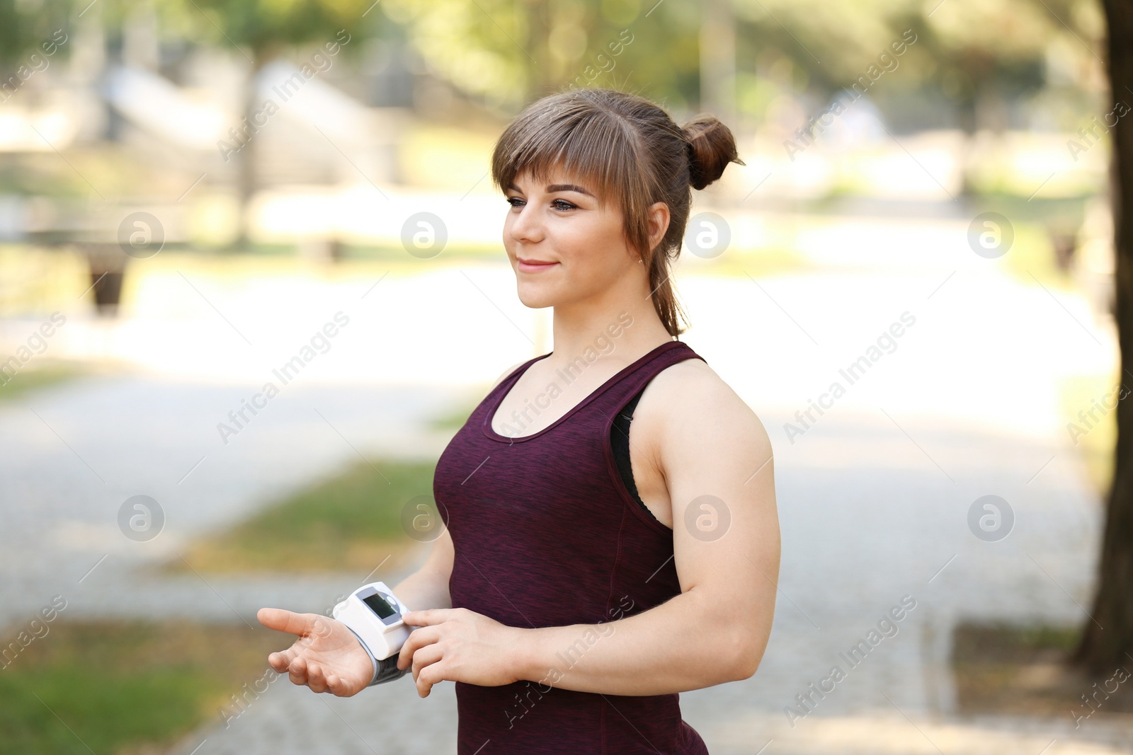 Photo of Young woman checking pulse after workout in park