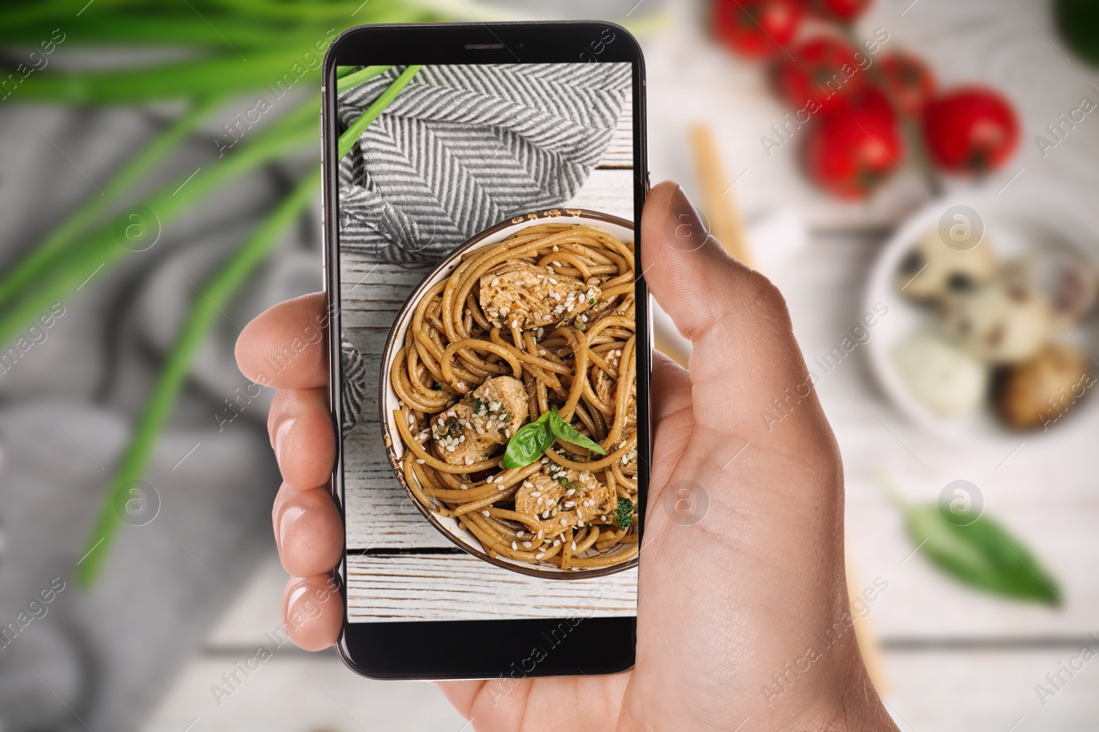 Image of Blogger taking picture of delicious buckwheat noodles with meat at table, closeup. Food photography