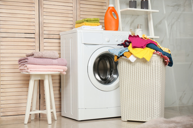 Basket with laundry and washing machine in bathroom