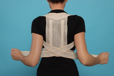 Photo of Closeup of woman with orthopedic corset on blue background, back view