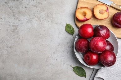 Photo of Delicious ripe plums on grey table, flat lay. Space for text