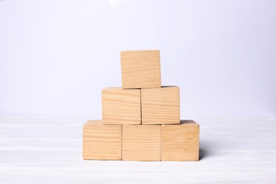 Photo of Pyramid of wooden cubes on white background, space for text. Idea concept