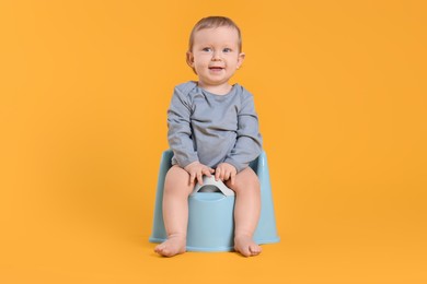 Photo of Little child sitting on baby potty against yellow background