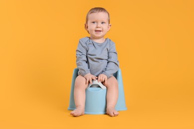 Little child sitting on baby potty against yellow background