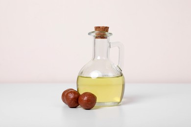 Photo of Delicious organic Macadamia nuts and natural oil on white background