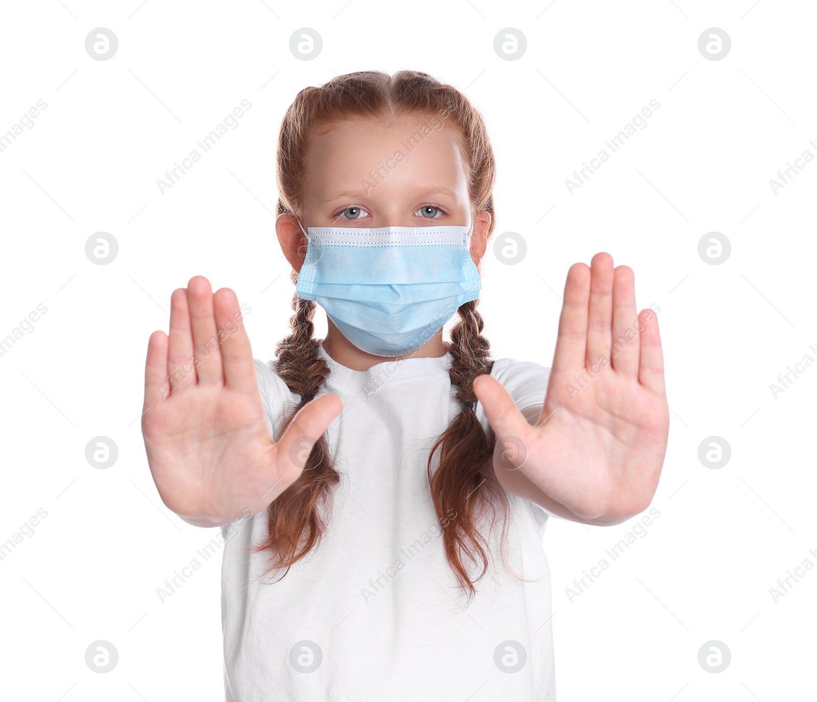 Photo of Little girl in protective mask showing stop gesture on white background. Prevent spreading of coronavirus