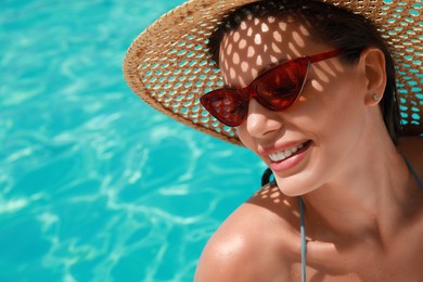 Beautiful woman wearing hat and sunglasses in swimming pool