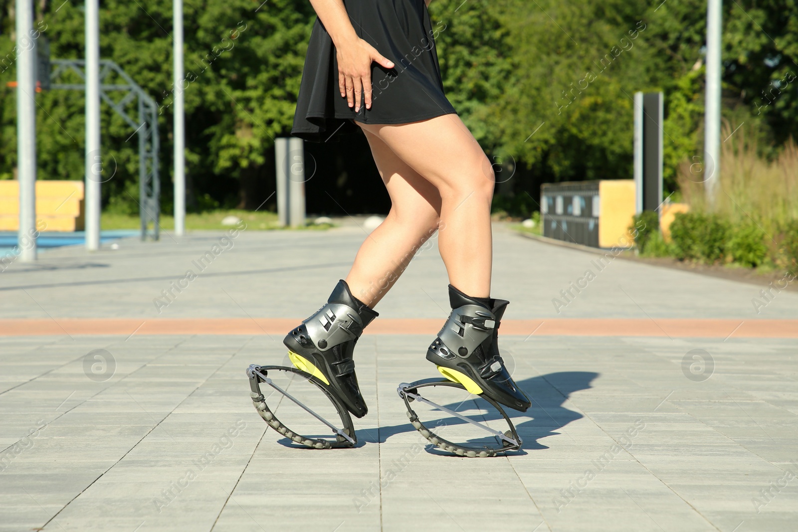 Photo of Woman doing exercises in kangoo jumping boots outdoors, closeup