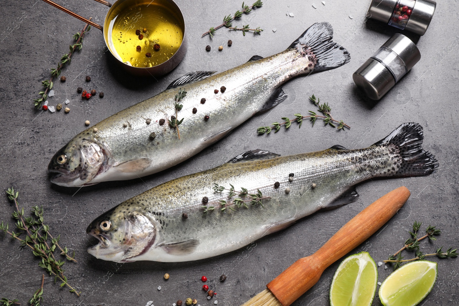 Photo of Flat lay composition with raw cutthroat trout fish on grey table