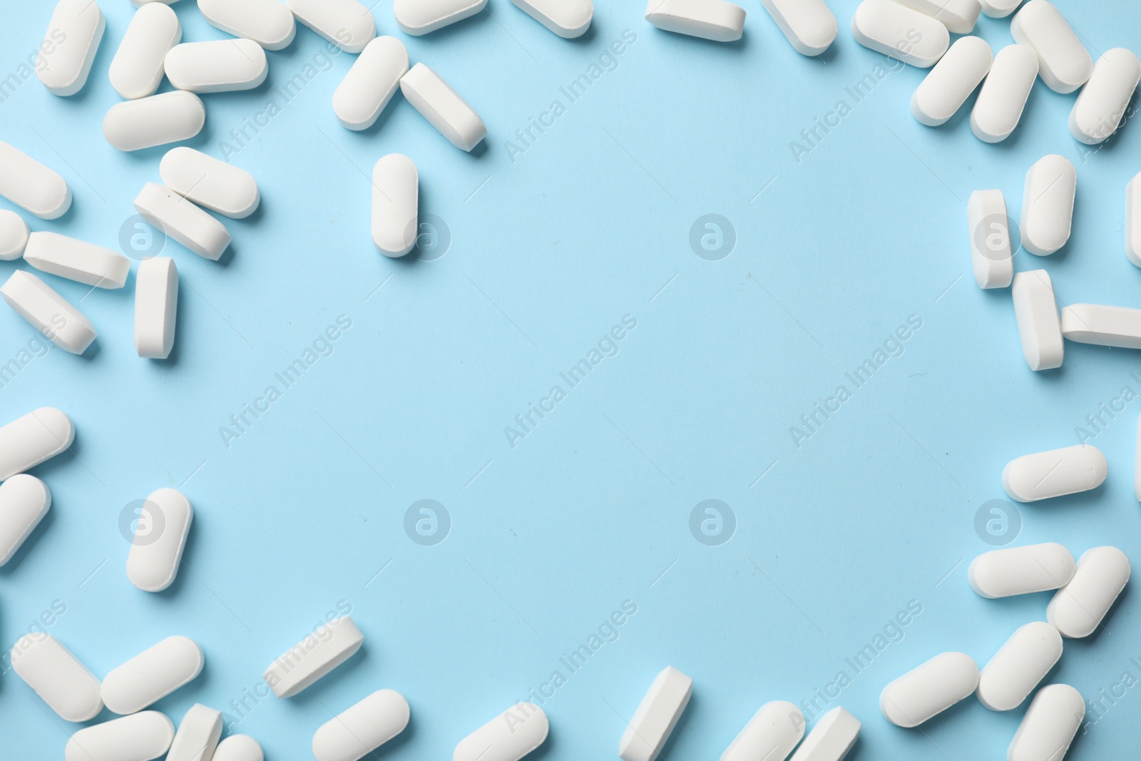 Photo of Frame made of vitamin pills on light blue background, top view. Space for text