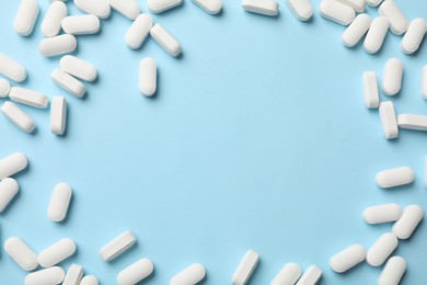 Photo of Frame made of vitamin pills on light blue background, top view. Space for text