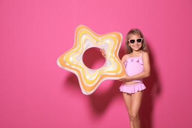 Cute little girl with bright star shaped inflatable ring on color background