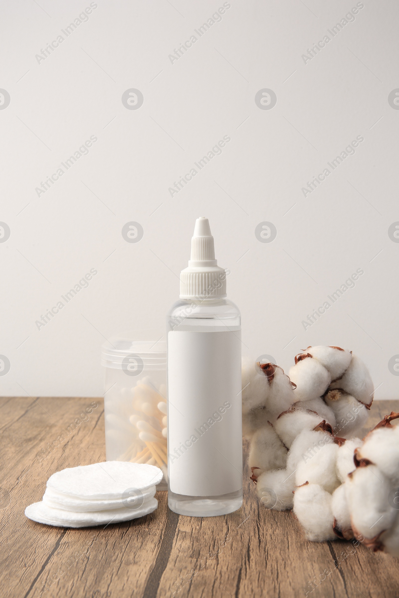 Photo of Composition with makeup remover and cotton flowers on wooden table against white background