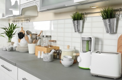 Photo of Different appliances, clean dishes and utensils on kitchen counter