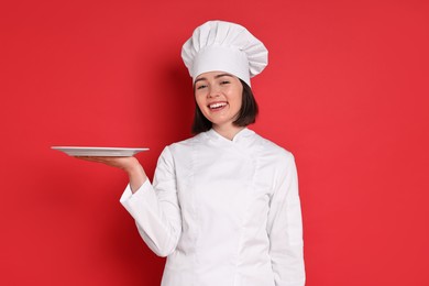 Photo of Happy confectioner with plate on red background