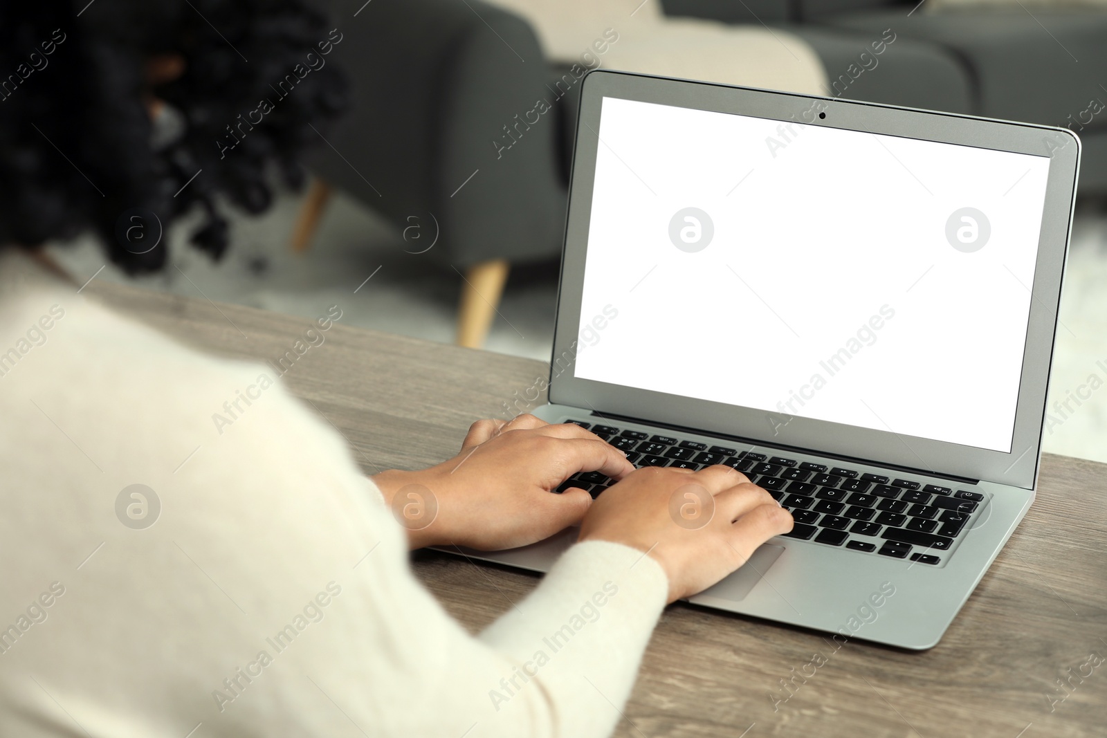 Photo of Woman using laptop at wooden desk indoors, closeup