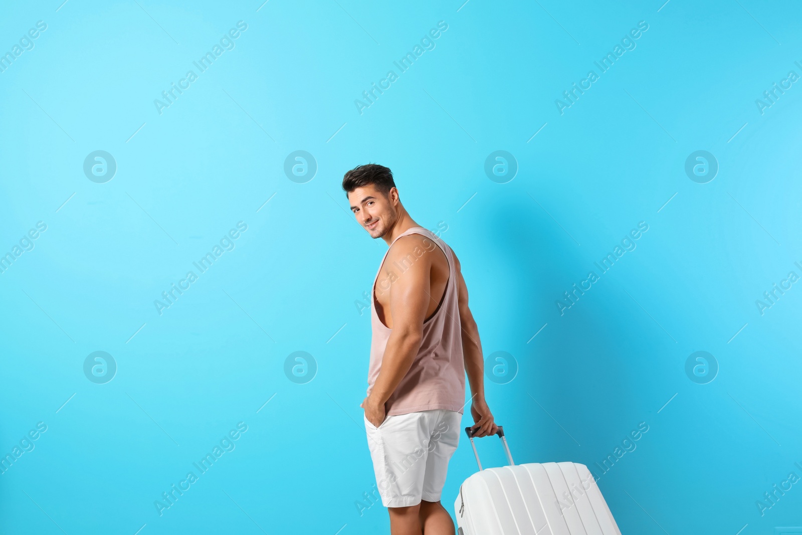 Photo of Young man with suitcase on color background