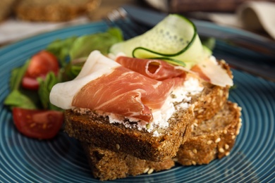 Plate of delicious bruschettas with prosciutto on table, closeup