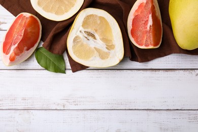 Photo of Different sorts of tasty pomelo fruits on white wooden table, flat lay. Space for text