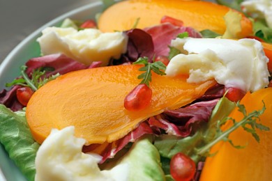 Photo of Plate of delicious persimmon salad with cheese and pomegranate, closeup