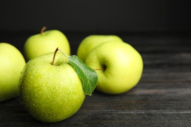 Photo of Fresh ripe green apples on black wooden table, space for text