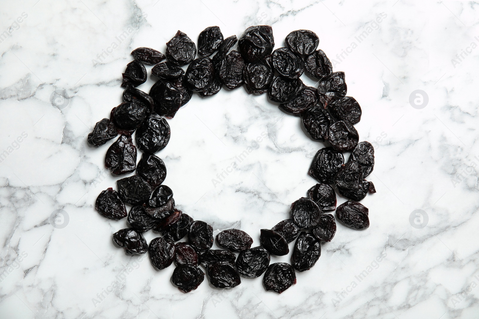 Photo of Frame of sweet dried plums on marble background, top view with space for text. Healthy fruit