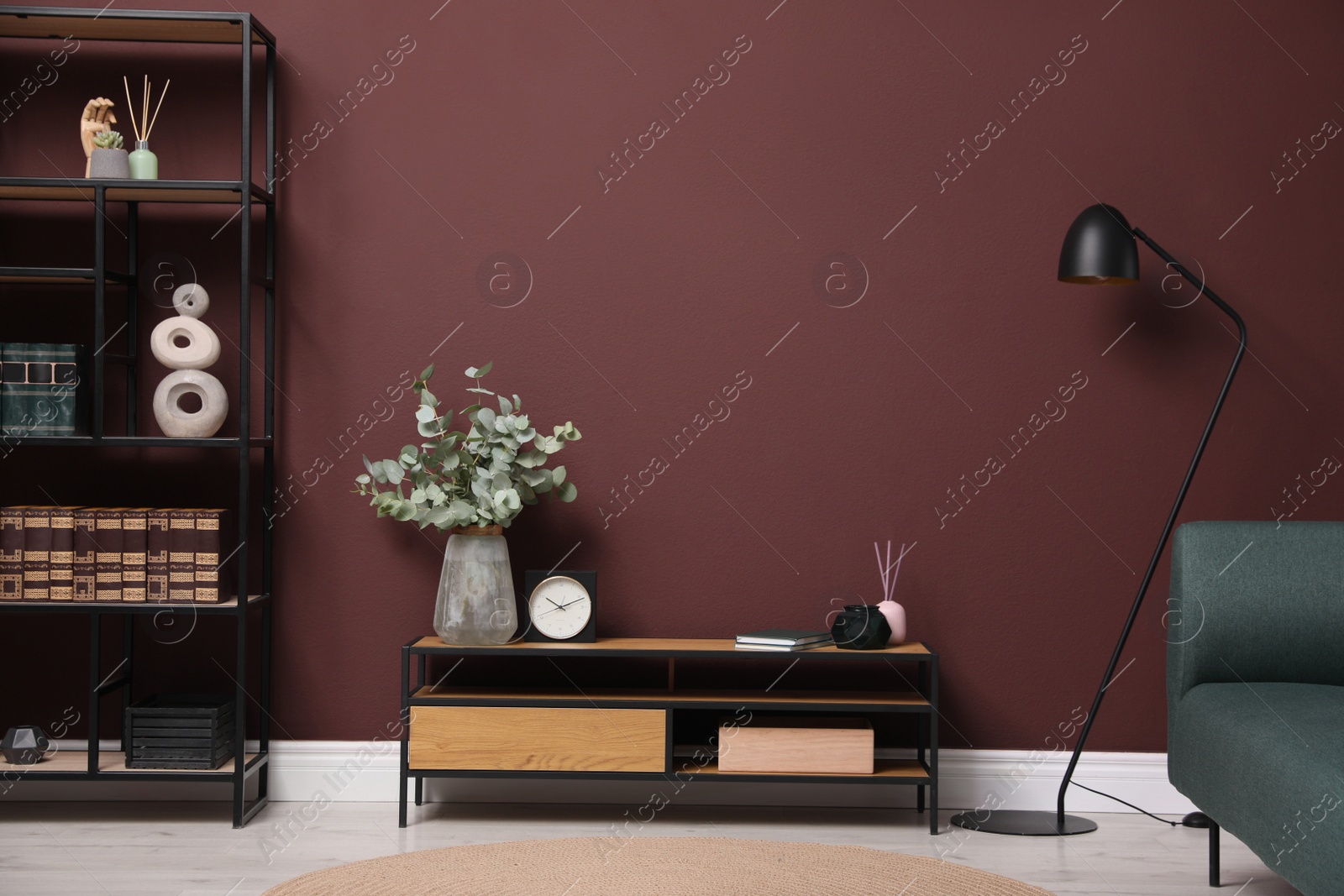 Photo of Elegant room interior with wooden cabinet, shelving unit and floor lamp near brown wall