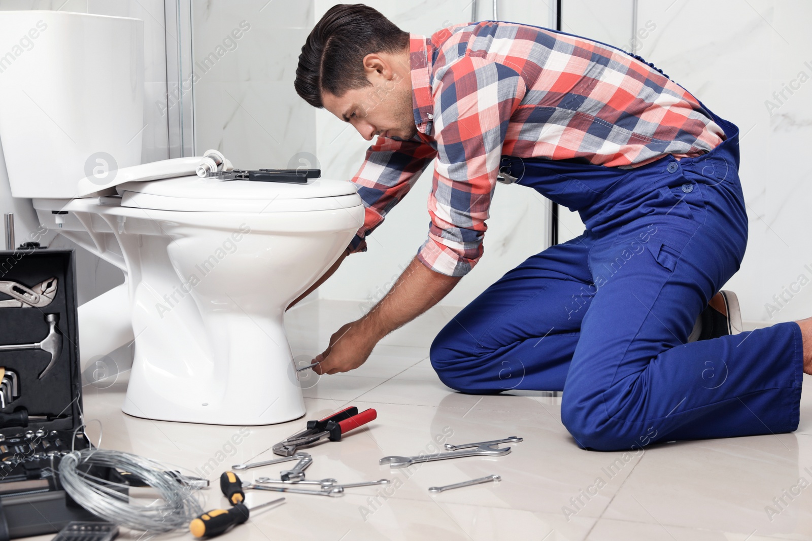 Photo of Professional plumber working with toilet bowl in bathroom