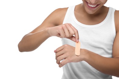 Photo of Man putting sticking plaster onto hand on white background, closeup