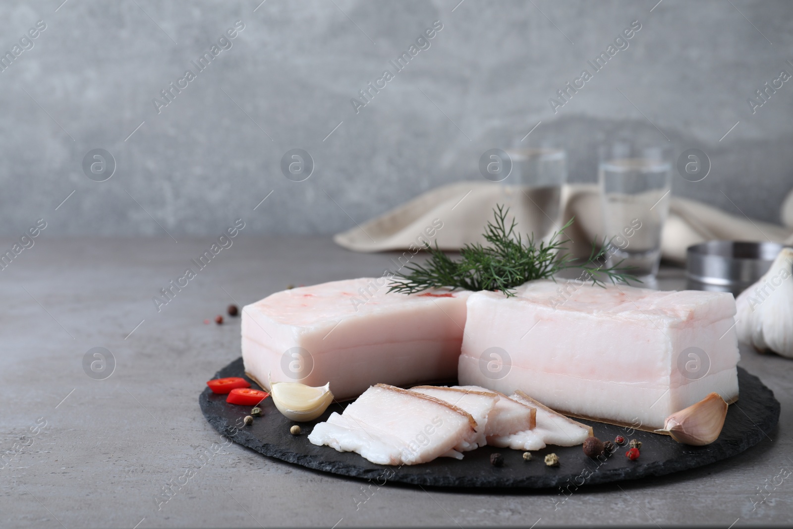 Photo of Pork fatback with spices served on grey table. Space for text