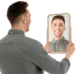 Photo of Young man holding mirror and looking at himself on white background