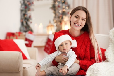 Happy mother with cute baby in room decorated for Christmas holiday