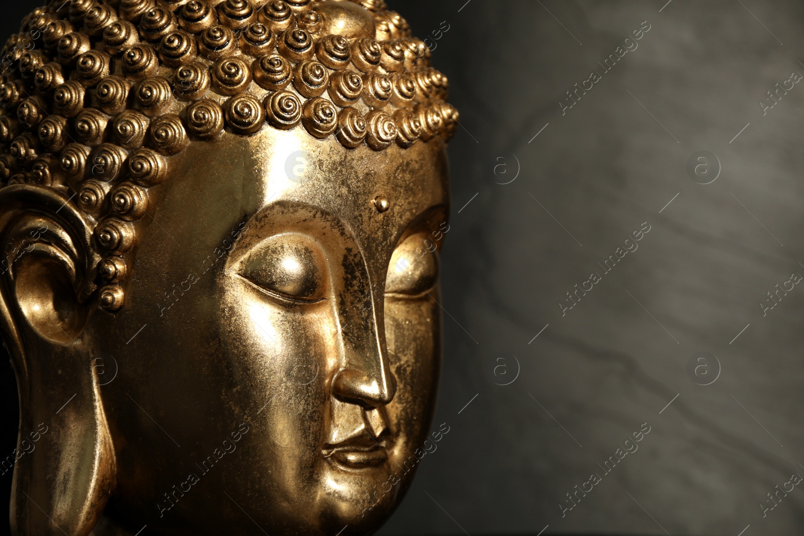 Photo of Buddha statue on dark background, closeup. Space for text