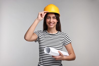 Architect with hard hat and draft on light grey background