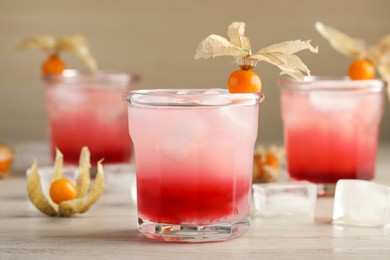 Photo of Refreshing cocktail decorated with physalis fruits on wooden table