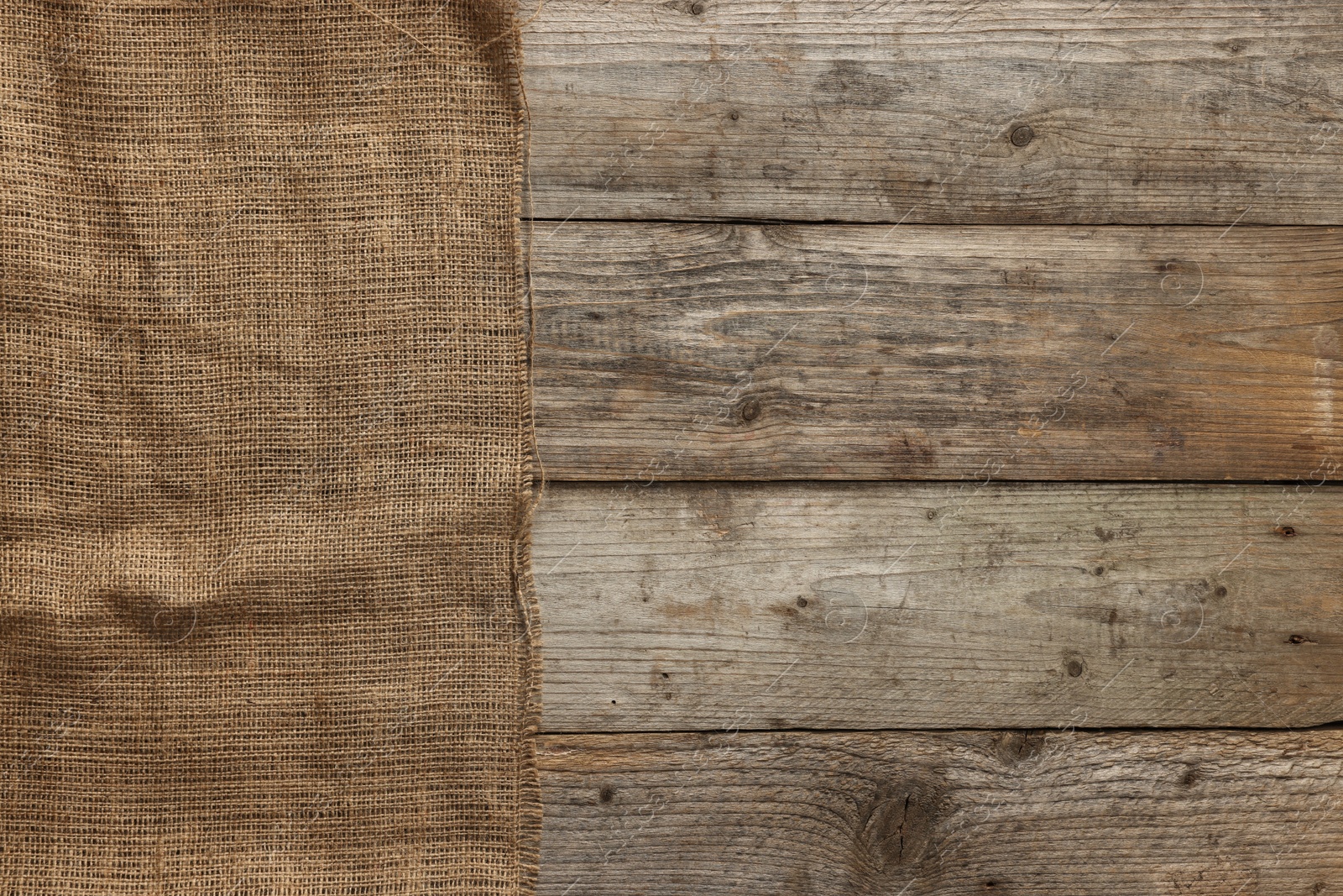 Photo of Burlap fabric on wooden table, top view. Space for text