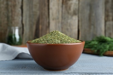 Photo of Dried dill in bowl on grey wooden table, closeup