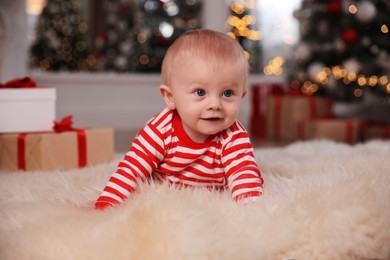 Photo of Cute baby in bright Christmas pajamas on floor at home