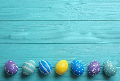 Photo of Flat lay composition of painted Easter eggs on wooden table, space for text