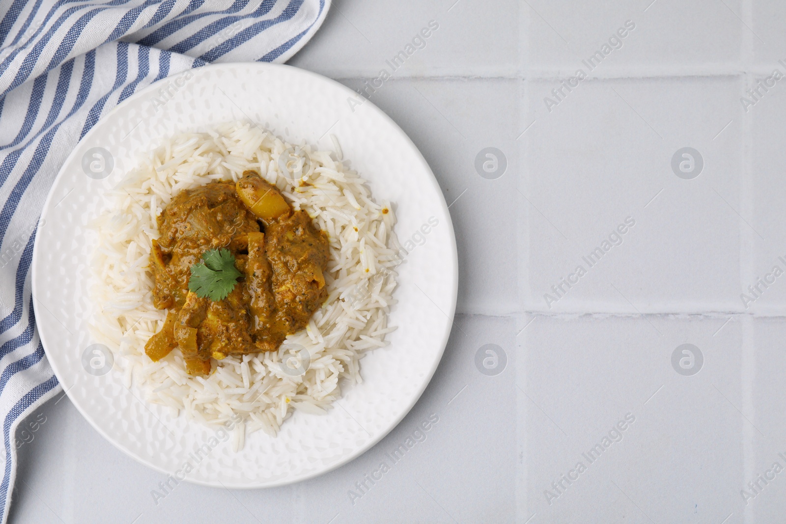 Photo of Delicious chicken curry with rice on white tiled table, top view. Space for text