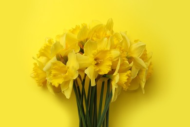 Photo of Beautiful daffodil bouquet on yellow background, top view