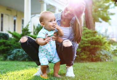 Teen nanny with cute baby on green grass outdoors