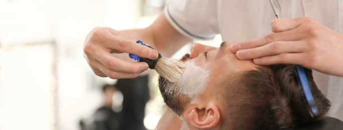 Image of Professional barber working with client in hairdressing salon. Banner design