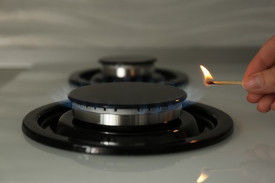 Woman lighting gas stove with match, closeup