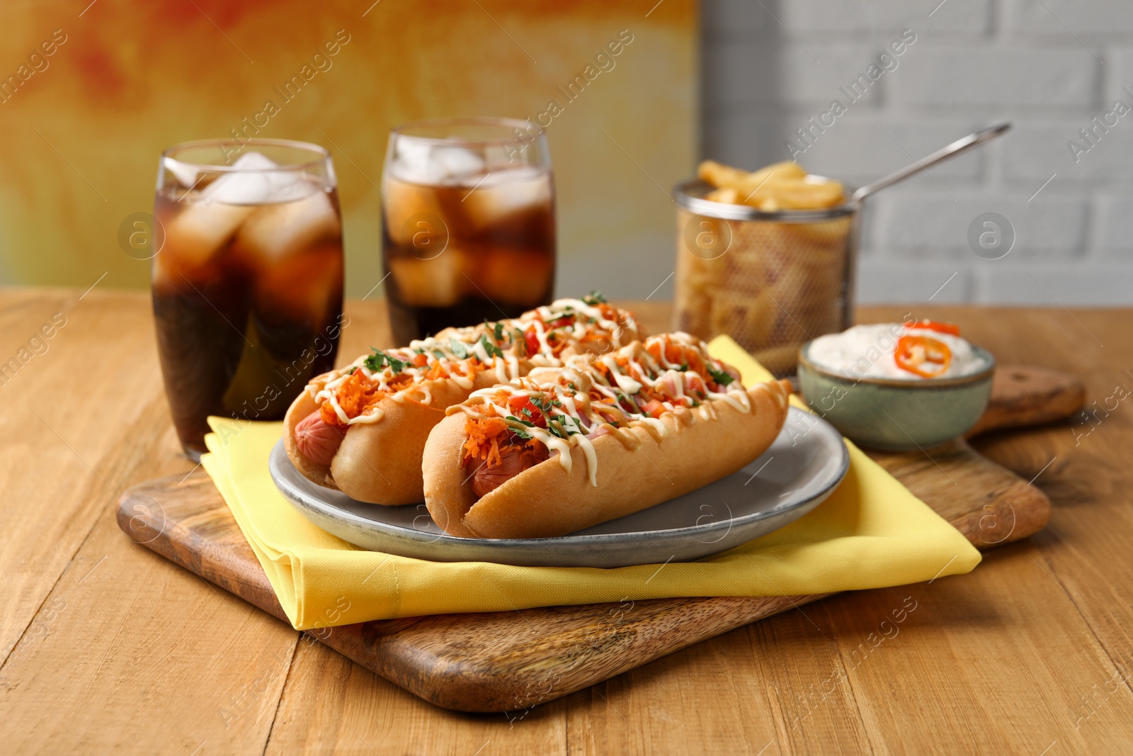 Photo of Delicious hot dogs with bacon, carrot and parsley served on wooden table