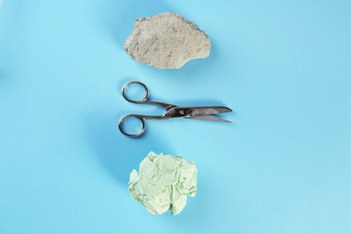 Photo of Flat lay composition with rock, paper and scissors on light blue background