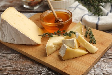 Photo of Tasty Camembert cheese with thyme and honey on wooden table