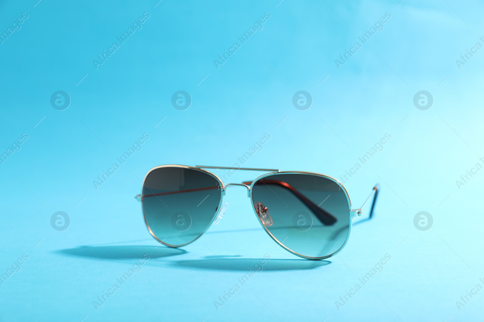 Photo of Stylish sunglasses on light blue background. Space for text